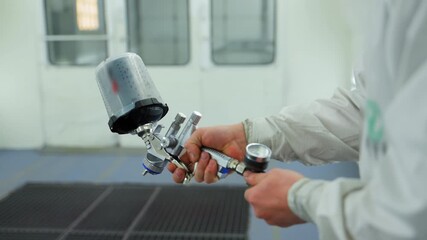 Professional auto body technician test spray gun inside a clean, well lit automotive paint booth. - Powered by Adobe