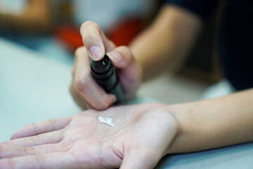 Obraz premium Close-Up of Pumping Topical Cream onto Hand