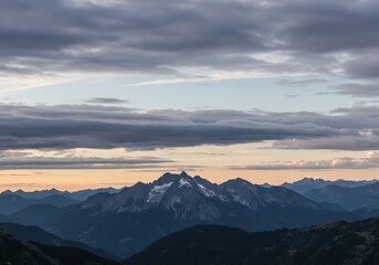 Majestic mountain range silhouette under a dramatic cloudy sky at sunset