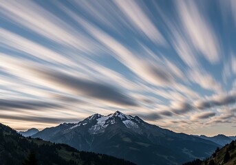 Obraz premium Majestic mountain range under a dynamic sky with long exposure clouds
