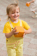 Happy toddler playing with an orange foam block outdoors