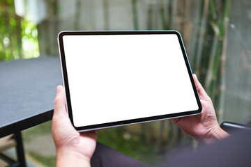 Mockup image of a woman holding digital tablet with blank white desktop screen in cafe