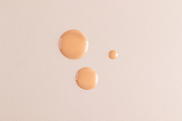 Three beautiful round drops of foundation on a beige background. top view. A copy of the space. Cosmetic texture sample. layout. template.