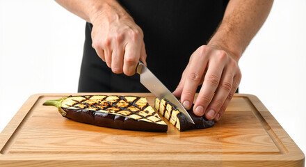 Man slicing grilled eggplant on wooden cutting board in kitchen  