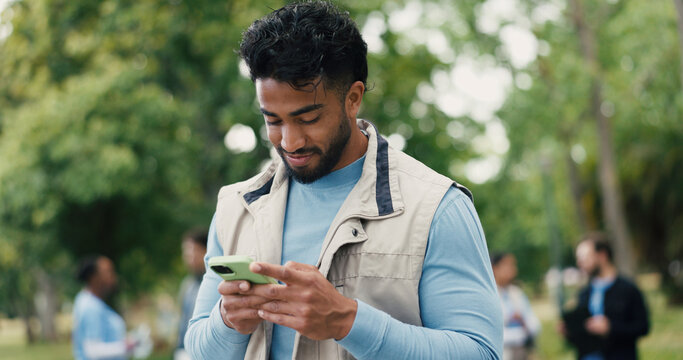 Agenda, phone and volunteer with man in park for charity, community outreach or food drive. App, schedule and typing with happy person outdoor for activism, donation or non profit communication
