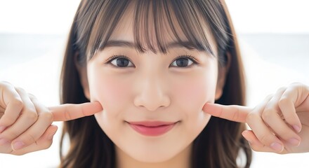 Happy Asian Woman with Fingers on Cheeks and Radiant Skin