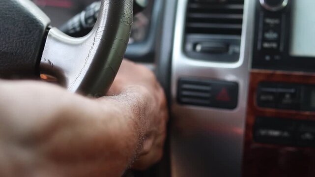 Male hand starting his car with a key. The man puts the key in the ignition and the vehicle starts.