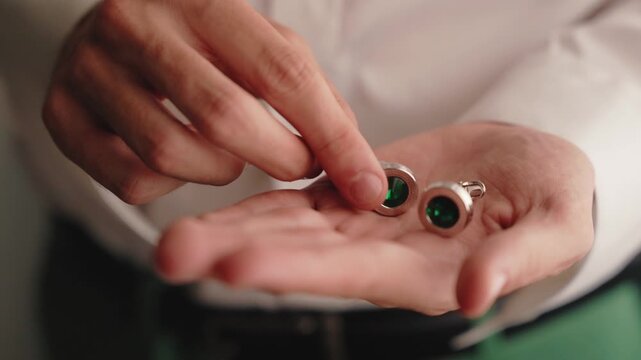close up of silver cufflinks with green stones in palm