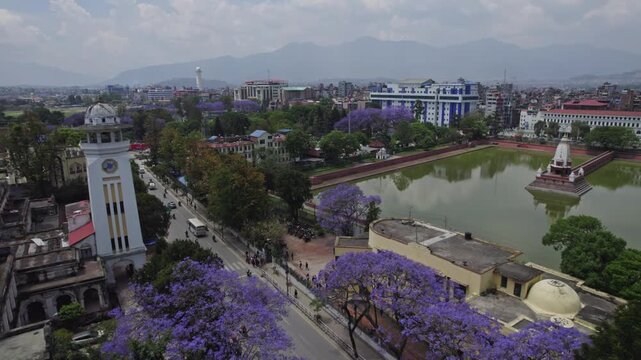 A beautiful drone view of Kathmandu Valley featuring Rani Pokhari, Ghantaghar, and blooming Jacaranda flowers. This aerial shot highlights the valley&rsquo;s culture, colors, heritage, and timeless urban.