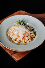 Delicious creamy fettuccine pasta served with fresh greens on a wooden board