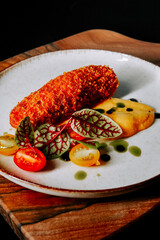 Delicious gourmet dish featuring fried croquette served on a rustic wooden plate