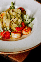Fresh shrimp fettuccine with cherry tomatoes and herbs on a rustic table setting