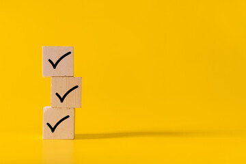 stack wooden blocks with checkmark symbol isolated on yellow background © Dadan