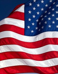 Obraz premium Close-up view of a national flag, its stripes and stars billowing in the wind against a deep blue sky