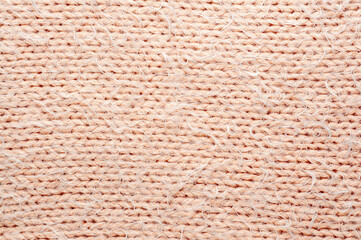 Close-up of a textured, beige knitted fabric, perfect for backgrounds and designs
