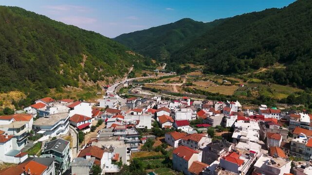 Cinematic aerial drone flight descending into the lush green Rhodope Mountain valley, approaching the isolated white houses of Echinos village, Xanthi, Greece.