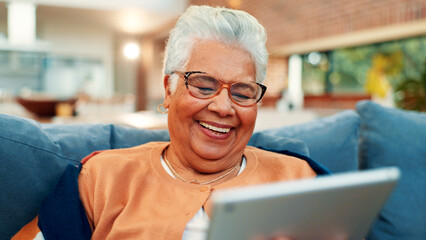 Tablet, happy and senior woman on sofa in home with networking, social media or blog post. Relax, digital technology and elderly female person in living room for reading news headline in house.
