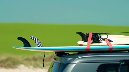 Surfboard strapped to car roof, with fins, against a green background