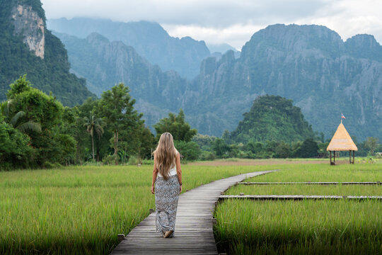 Woman walking on wooden path in laos rice field