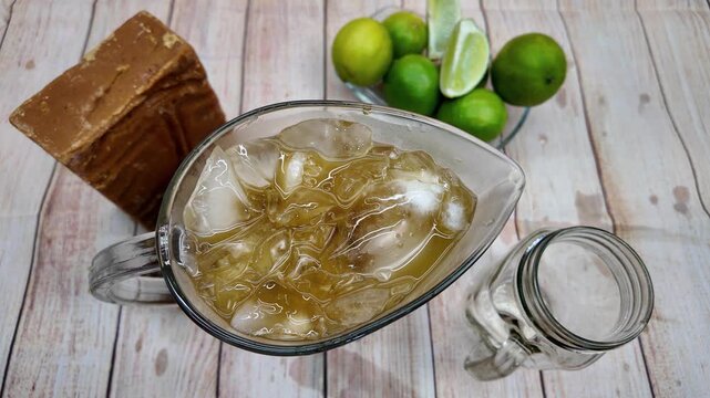 Top-down view of hand pouring traditional Venezuelan Papel&oacute;n con Lim&oacute;n into glass