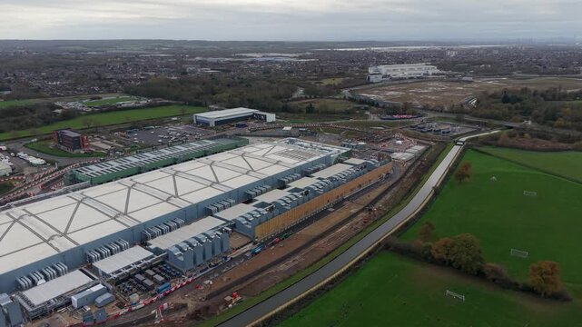 Sideways drone pan over the rear of the Google Data Centre in Waltham Cross, Hertfordshire. Captures the full scale of the facility, surrounding greenery, and infrastructure.