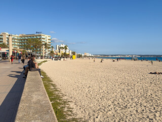 People sitting on a stone wall at Playa de palma at Can pastilla on Mallorca