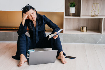 A woman appears contemplative, resting her head on her hand, deeply immersed in thought while...