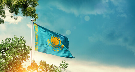 Kazakhstan national flag waving in the sky behind the tree. The flag blowing with beautiful sunlight. Kazakhstan national flag for independence day.