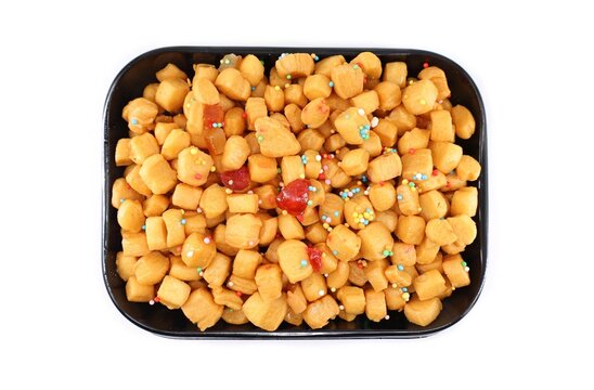 Struffoli, also known as Honey balls, in a black serving tray on white background. It is a traditional Neapolitan christmas dish.