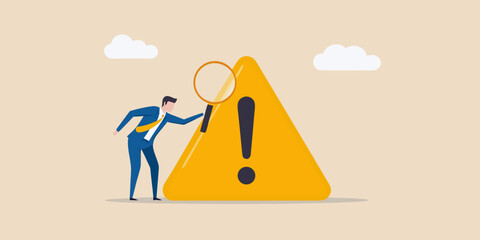 Businessman inspecting a warning sign with a magnifying glass risk assessment
