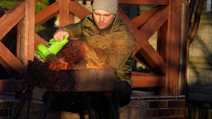 A man works at home, a man works on the site, daily chores in the house. Men's chores. A man lights the coals with a leaf blower.
