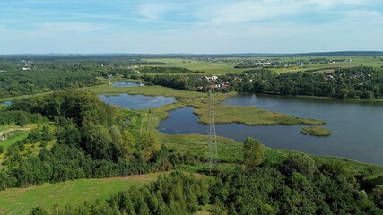 Obraz premium Aerial view of power tower near lake and trees