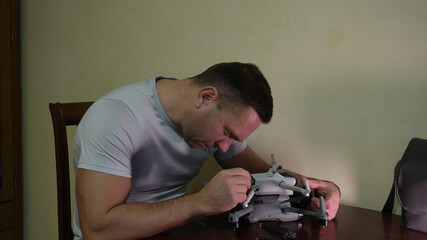 A man repairs drones at home. Working on quadcopters.