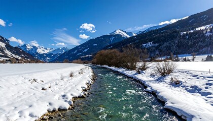 A clear stream runs through a snowy valley floor, with snowy mountains towering under a bright blue sky
