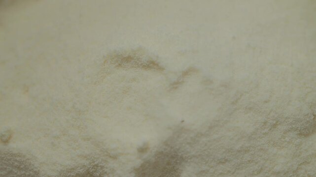 Powdered milk is poured smoothly into a container, creating a soft cascade of fine powder. This simple kitchen process showcases the easy handling of milk powder.