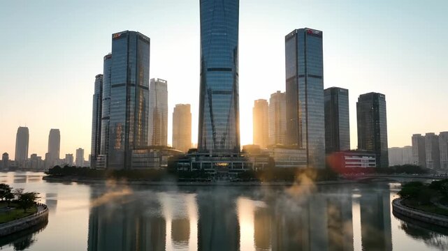 Sunrise lights city skyline reflection. Skyscraper tower rises above calm river. Modern architecture frames waterfront view. Business district shows corporate skyline. Golden sunlight softly reflects.