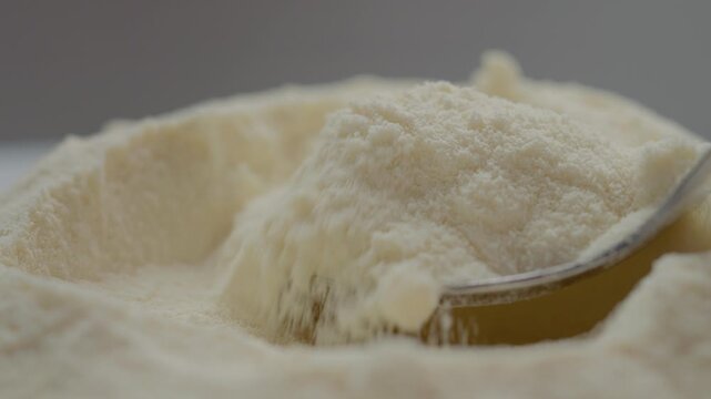 A spoon fills itself with soft powdered milk, showcasing the fine texture of the milk as it smoothly rises. Perfect for cooking and baking various dishes.