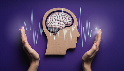 Hands hold brain cutout. Paper head with encephalography on purple background. Alzheimer, autism awareness, stroke, epilepsy, ADHD, seizure disorder, mental health challenges concept. Support
