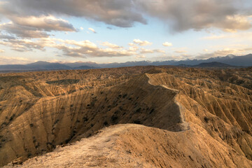 Sunset light over the dramatic ridges of Ak-Say Canyon in the Issyk-Kul region of Kyrgyzstan, highlighting its rugged textures and vast mountainous landscape.