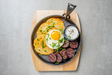 A tasty breakfast of golden eggs, blood sausage, and crispy herb-garnished potato patties