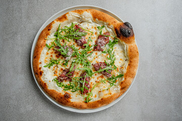 Delight in a freshly baked white pizza featuring creamy cheese, arugula, and flavorful meats