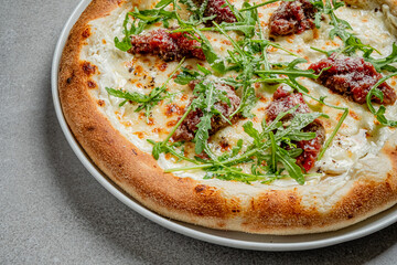 Delicious pizza features creamy sauce, tender toppings, and fresh arugula on a rustic table setting