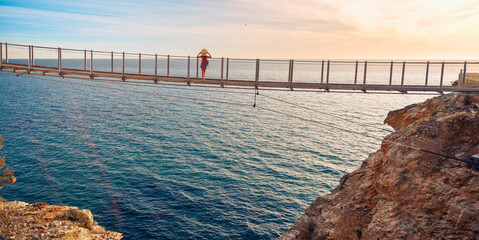 Carefree woman on suspension bridge looking at the sea. Torrenueva, Granada province in Spain....