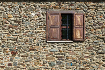 The harmony of wooden windows and stone walls. Stone-walled structures with wooden shutters....