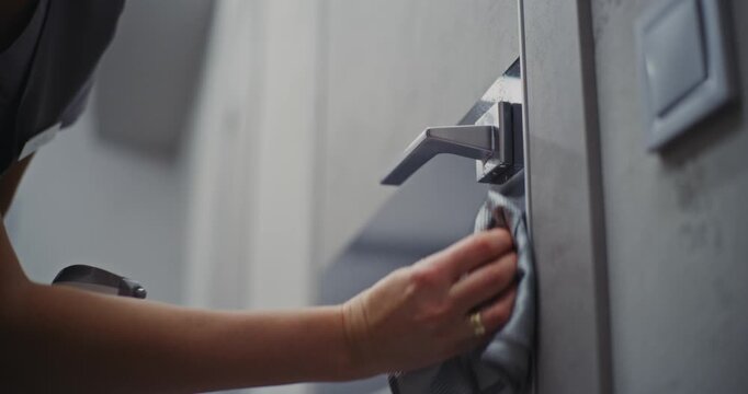 Close Up of Gentle, Precise Cleaning. Hotel Housekeeper Carefully Wipes Door Surface, Handle, Lock With Soft Cloth and Cleaning Spray. Concept Hygiene, Hospitality Standards, Guest Room Preparation.