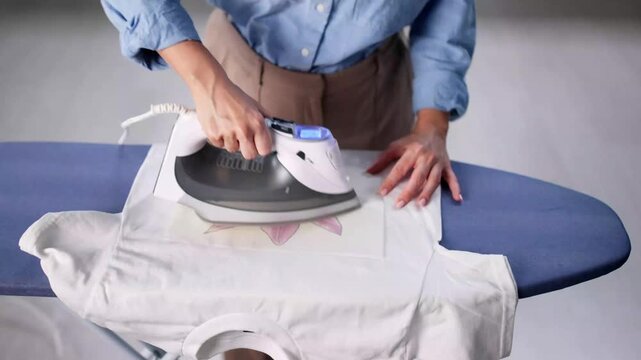 Woman Doing T Shirt Print Transfer Using Iron Appliance