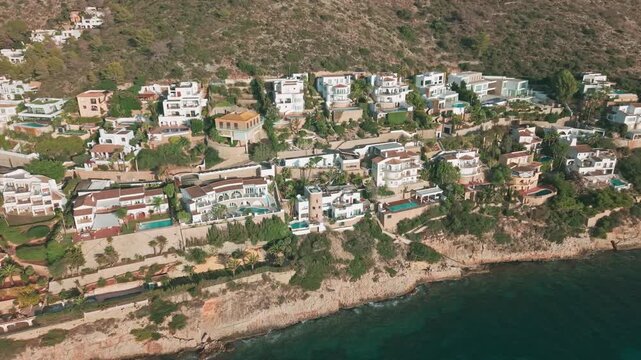 Drone footage of luxury cliffside villas with swimming pools in Moraira, Costa Blanca, Spain. Scenic Mediterranean coastline with elegant architecture and turquoise sea.
