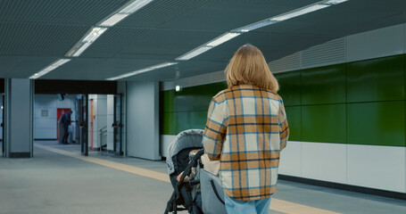 Young mother gently pushing baby stroller, navigating urban subway station platform with care and confidence during daily commute