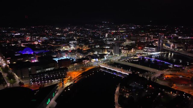 Wide reversing 4K 60FPS aerial of Belfast City Centre and the River Lagan on a calm night. Produced with Rec709 color.