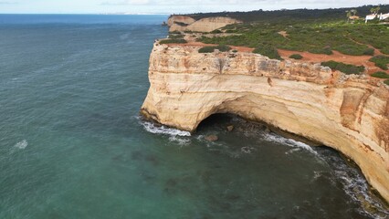 Rocky coastal cliff with natural arch in Faro, Algarve, Portugal